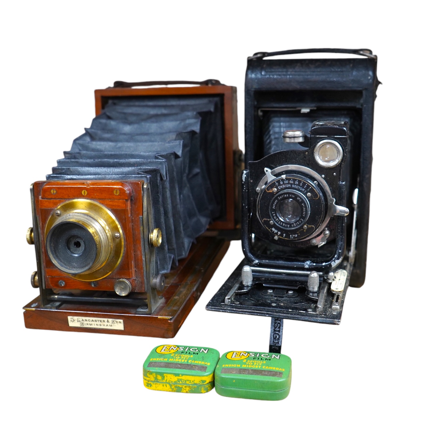 Two cameras; one late 19th century by Lancaster & Son, together with an Ensign bellows camera with two tins of spools of film. Condition - fair to good